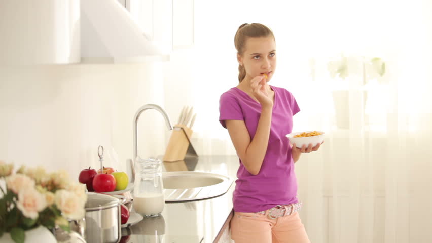 Girl holding a bowl with cornflakes and smiling
