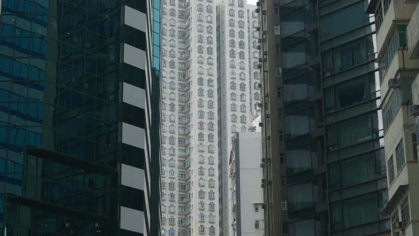 Panoramic view of apartment buildings and skyscrapers in downtown Hong Kong, China on a sunny day, showcasing dense urban living and modern architecture.