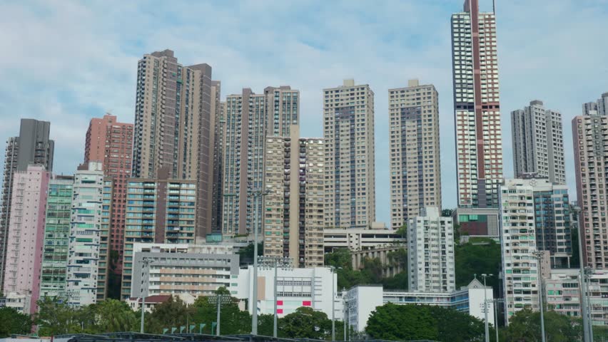 Panoramic view of apartment buildings and skyscrapers in downtown Hong Kong, China on a sunny day, showcasing dense urban living and modern architecture.