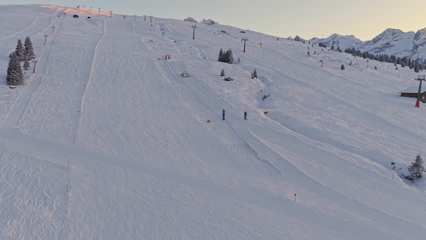 Aerial footage of Zillertal Arena showing pistebully machines shaping ski runs in Krimml and Königsleiten, Austria, with deep snow and panoramic alpine peaks.