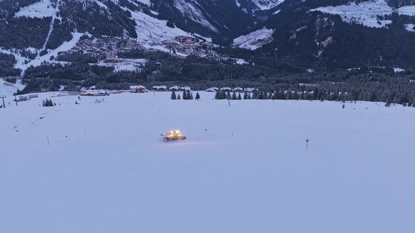 Drone shot of Zillertal Arena showing snow groomers shaping ski runs in Krimml and Königsleiten, Austria, with snow covered terrain.