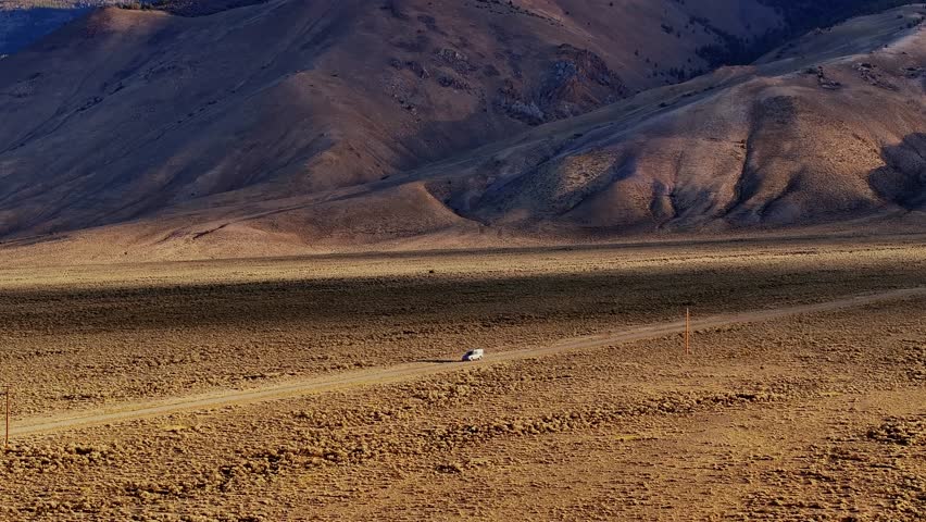 Broad Idaho valley floor with Borah Peak rising beyond dry grasslands