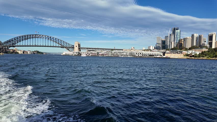 Sydney, Australia: Point of view of a public ferry that sails on the Sydney bay with the city skyline and Sydney harbor bridge in the background on a sunny day toward Balmain area