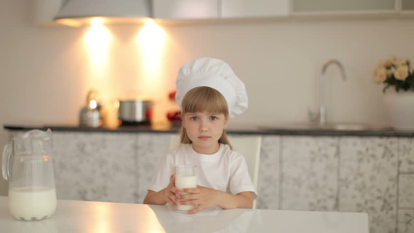 Little girl sitting in kitchen and she going to drink milk
