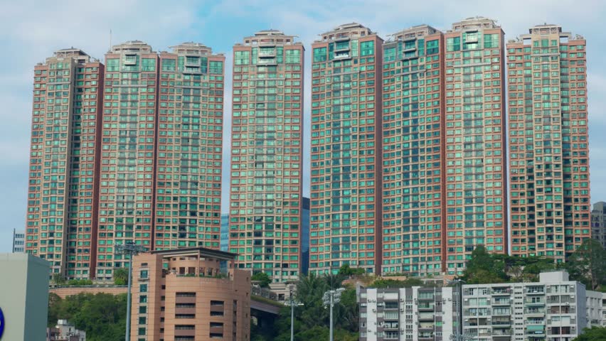 Panoramic view of apartment buildings and skyscrapers in downtown Hong Kong, China on a sunny day, showcasing dense urban living and modern architecture.