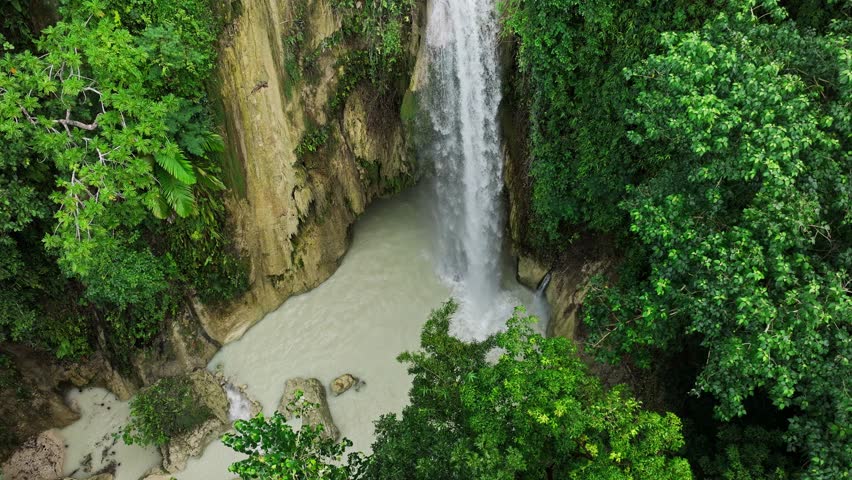 Drone pulls back revealing Inambakan Falls and muddy water after the typhoon