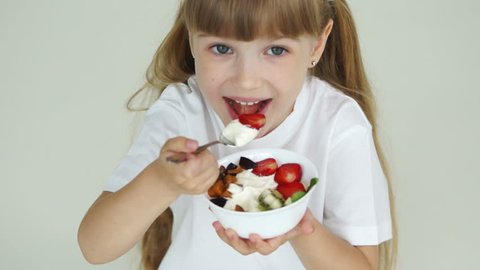 Little girl with fruit yogurt looking at camera and laughing
