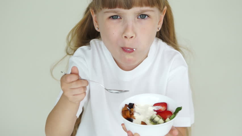 Little girl eating yogurt with fruit
