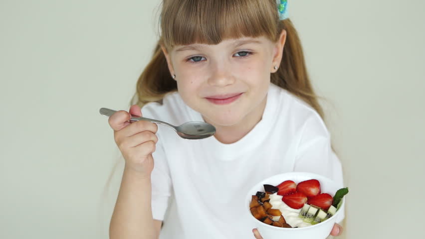 Girl with fruit yogurt looks at the camera and smiling
