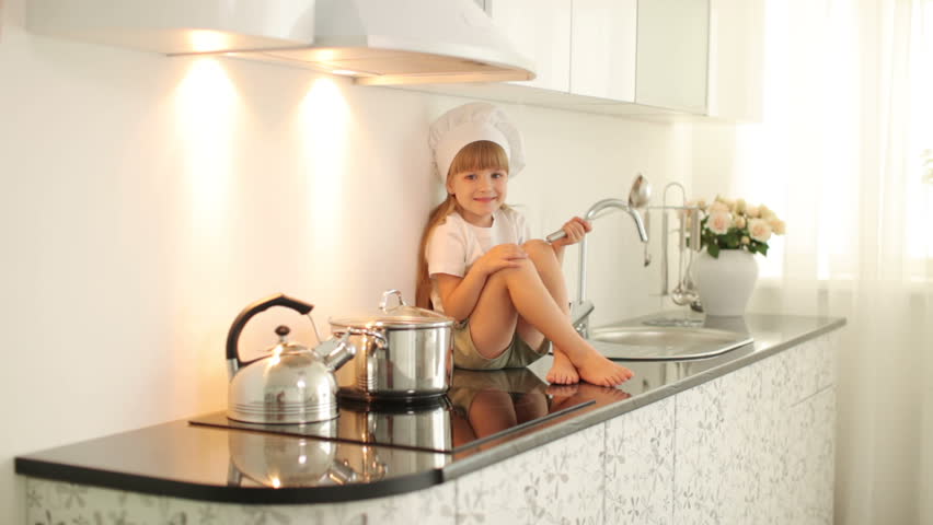 Little girl sitting with a ladle in the kitchen
