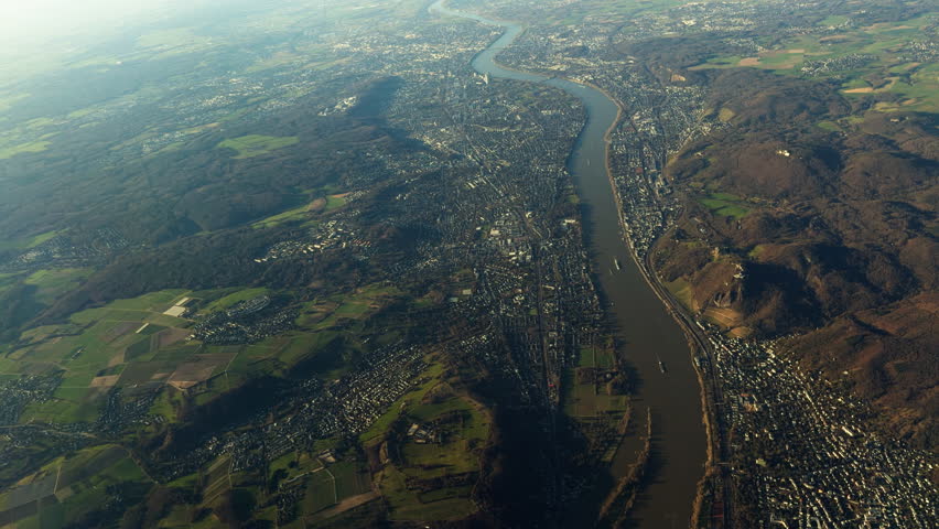 Aerial view of the Rhine River flowing through cities and countryside near Cologne, Germany. Landscape showing urban areas, farmland and hills along one of Europe’s major waterways.