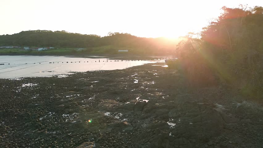 A beautiful sunset over a beach with a few people and a boat in the water