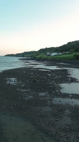 Dark pebbles line wet shoreline after low tide