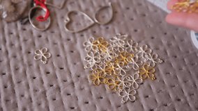 Hand Dropping Gold Filigree Flower Charms onto Pile of Jewelry Findings on Craft Table, Handmade Jewelry Making Process Close Up - Powered by Shutterstock - Get 15% off with code: PIKWIZARD15