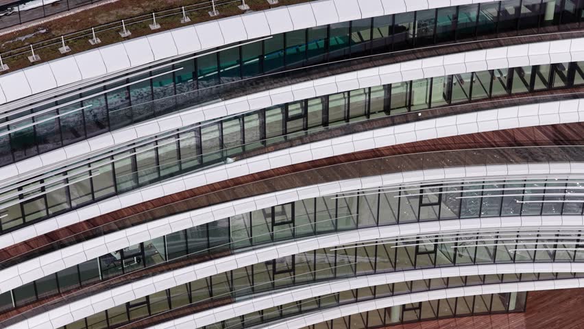 Aerial drone view of a modern office building with angular architecture, rooftop terrace, wooden deck flooring, and green roof elements in Vilnius, Lithuania.