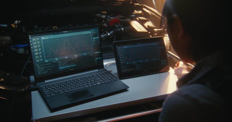Woman Uses Dual Screen Setup, Featuring Laptop and Tablet, to Monitor Complex Engine Performance Graphs and Sensor Logs Simultaneously. Software Driven Car Maintenance, Advanced Technical Expertise.