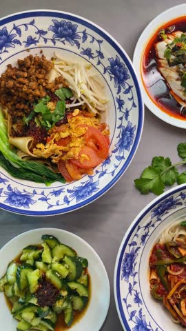 Sichuan appetizer spread with spicy tofu in chili oil, cold cucumber salad, marinated mushrooms and noodle side dishes on blue