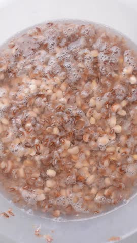 Overhead view of beans being washed, top view of honey beans being washed to make nigerian moi-moi or bean cake, process of peeling beans skin by hand