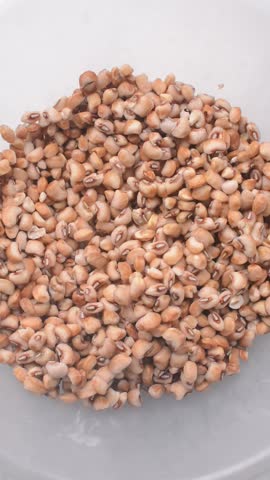 Overhead view of beans being washed, top view of honey beans being washed to make nigerian moi-moi or bean cake, process of peeling beans skin by hand