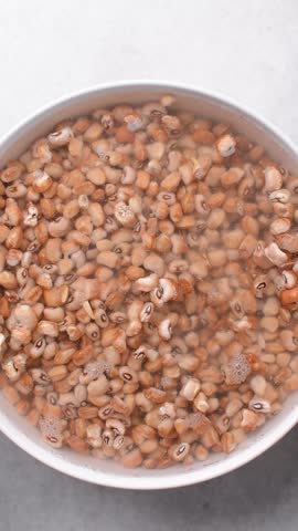 Overhead view of beans being washed, top view of honey beans being washed to make nigerian moi-moi or bean cake, process of peeling beans skin by hand