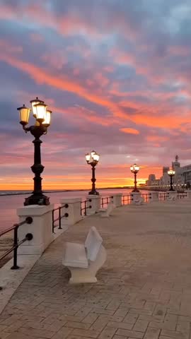 A stunning 4K vertical POV shot of the famous Lungomare di Bari promenade in Italy. The video features the iconic street lamps, the wide pedestrian walkway, and the turquoise Adriatic Sea. This footage perfectly captures the serene Mediterranean atmosphere of Southern Italy. Ideal for luxury travel content and social media storytelling