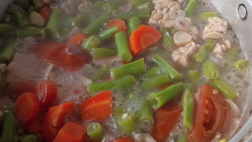 close sour bean and carrot soup, clear soup dish with beef cooking in pan