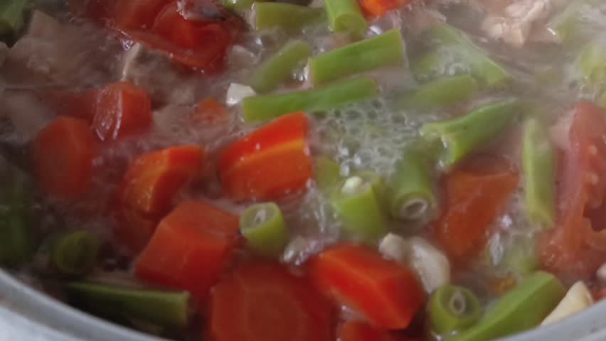 close sour bean and carrot soup, clear soup dish with beef cooking in pan
