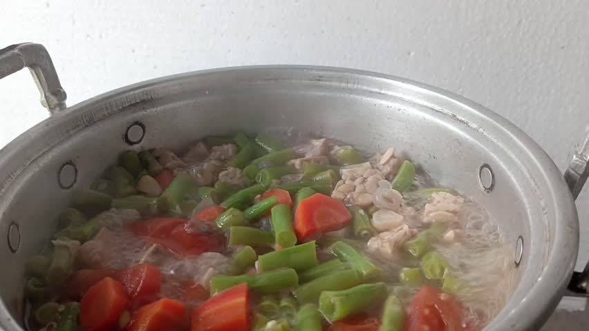 close sour bean and carrot soup, clear soup dish with beef cooking in pan