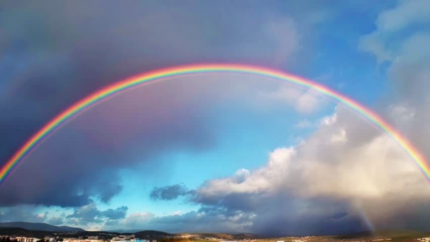 Colorful rainbow arching across dramatic sky after rainfall with soft clouds and warm sunlight breaking through, vibrant atmospheric weather phenomenon creating serene natural landscape and hopeful mood captured in cinematic ultra detailed 4K nature scenery.