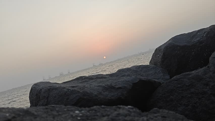 Time‑Lapse Sunset Over Ocean with Rocky Shoreline and Distant Ships