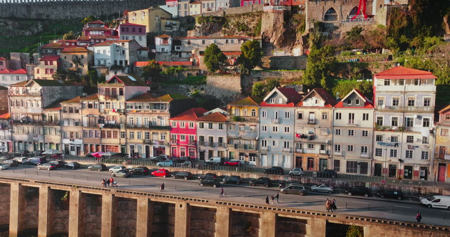 Porto historic Ribeira district with colorful traditional houses buildings and hillside architecture, with people walking on the riverfront promenade along the Douro River in Portugal. Panoramic shot