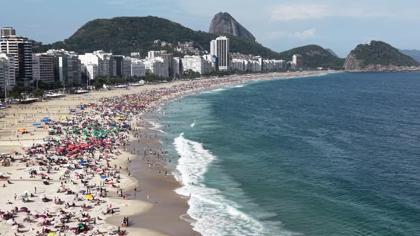 Rio de Janeiro, Brazil, aerial view of Copacabana Beach showing colourful umbrellas and people bathing in the ocean on a summer day. Tropical travel and vacation concept.