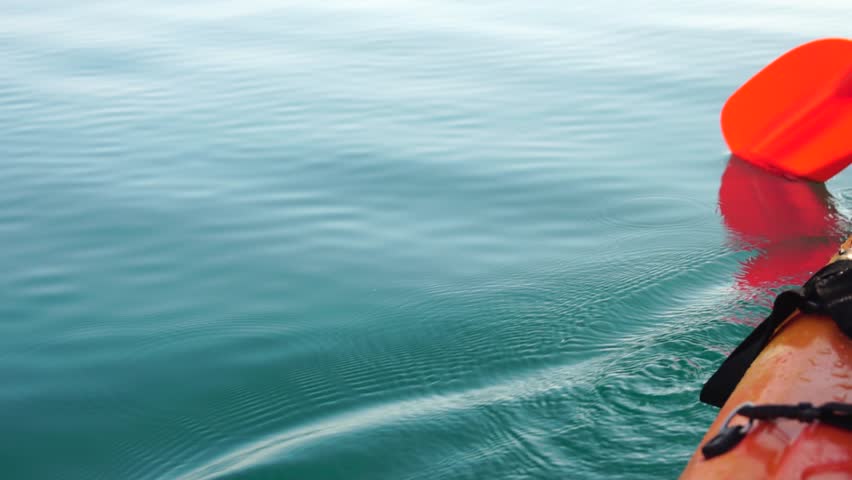 Kayaking water ocean, person paddles orange kayak on calm clear blue sea surface, peaceful summer activity