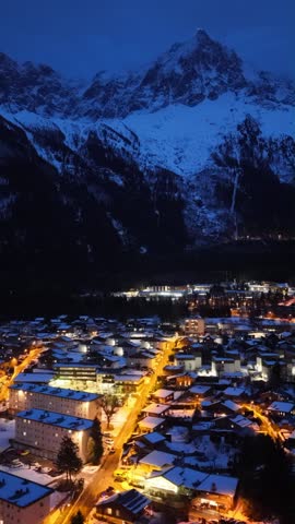 Nighttime Chamonix town glowing under snowy Mont Blanc mountains