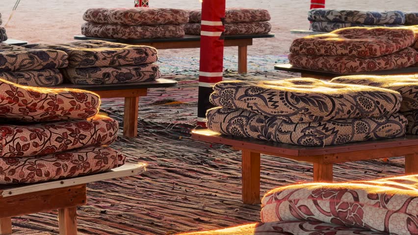 Close Up of Stacked Traditional Arabic Patterned Cushions on Low Wooden Tables inside Bedouin Dining Tent