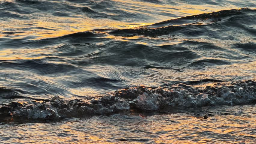 Close Up of Golden Sunlight Reflecting on Rippling Sea Surface with calm waves