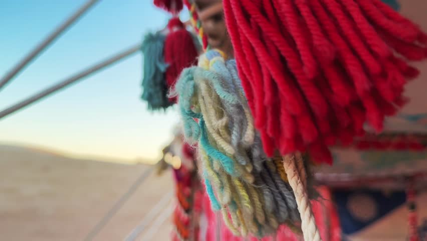 Close Up motion through Colorful Decorative Tassels swaying in the wind on Bedouin Tent ceiling with Blue Sky in Background