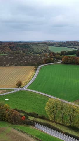 Drone footage of a rural landscape with fields and a road junction