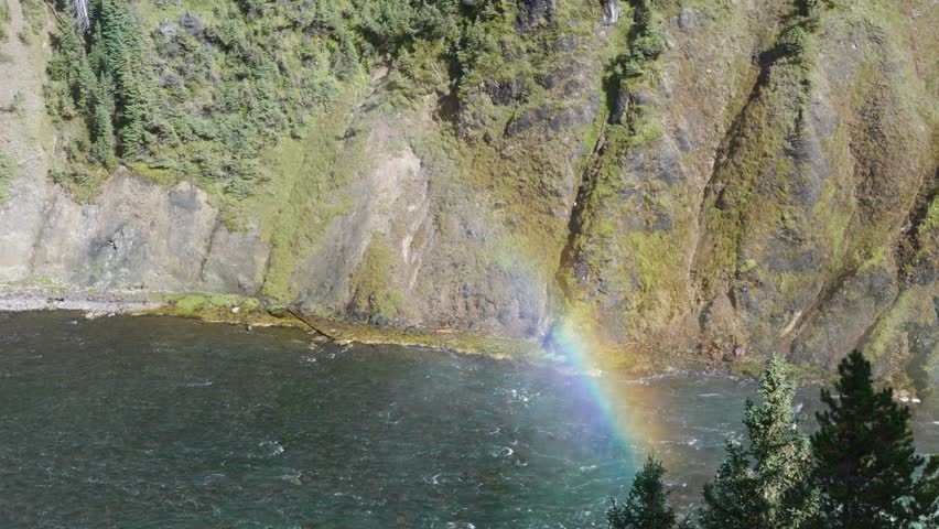 Rainbow forming above river flowing along rocky canyon wall in Yellowstone National Park, Nature travel, Scenic landscape