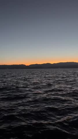 A mesmerizing shot of sunset afterglow reflecting on the rippling water surface. The contrast between the deep blue waves and the orange sky creates a peaceful and cinematic atmosphere. Perfect for meditation, background visuals, or travel vlogs.