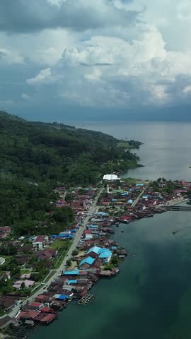 Aerial view of a beautiful and aesthetic settlement near a lake and mountains in Poso, Indonesia. Captured in the afternoon from a height using a drone.