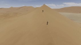 Drone flies low over the backs of hikers as the summit Dune 45 on windy and on sunny day in Sossusvlei, Namibia - Powered by Shutterstock - Get 15% off with code: PIKWIZARD15