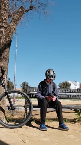 Young cyclist with helmet using smartphone before riding