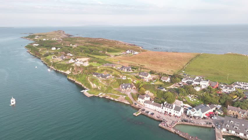 Overhead view of villageand rugged coastline in Ireland. Vast Atlantic Ocean and a rocky, green peninsula.