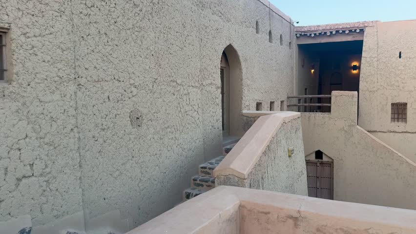 Historic Bahla Fort built with traditional mud architecture standing on rocky ground under clear blue sky showing ancient Omani heritage. Bahla, Oman - February 17 2026