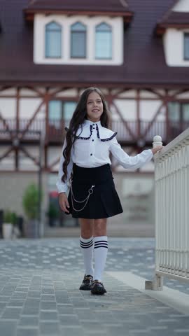 A girl in a stylish outfit walks outdoors. School clothes concept.