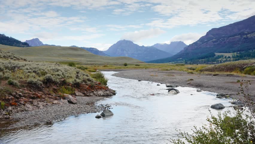 River flows gently through a wide valley surrounded by sagebrush plains and mountain ridges in Yellowstone National Park wilderness, Nature landscape, Travel tourism