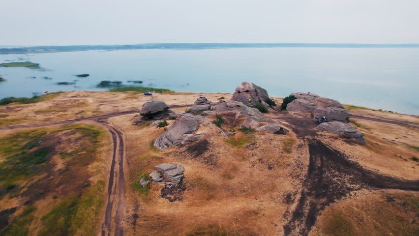 Aerial orbiting shot of strange rocky formations on a hill near a lake