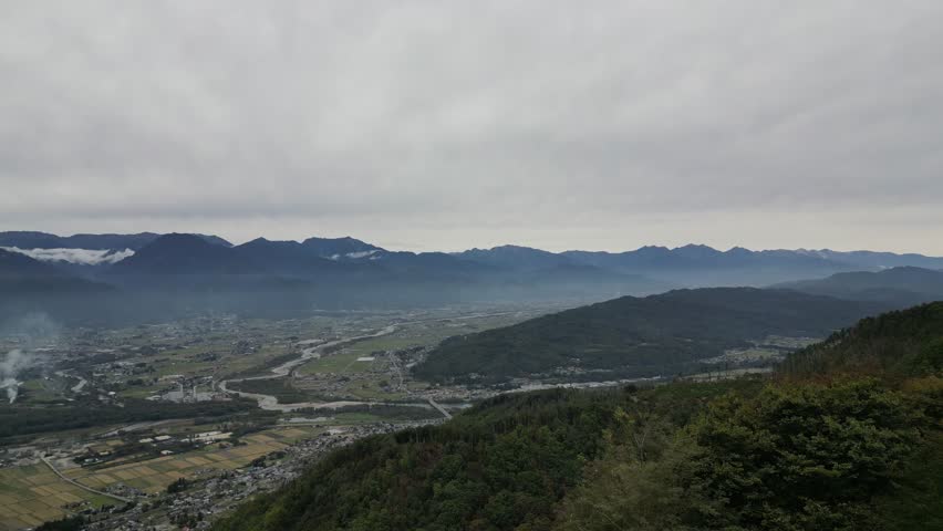 Drone aerial view of Nagamineyama Observatory overlooking Azumino city and the Northern Japanese Alps in Nagano, Japan. Scenic panoramic landscape of mountains and countryside.