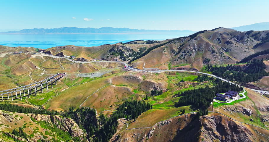 Aerial view of Sayram Lake and winding mountain highway in Xinjiang, China.
